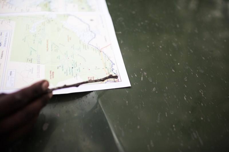 a close up of a persons hand pointing to a location on a map with a stick, taking the road less traveled 4k