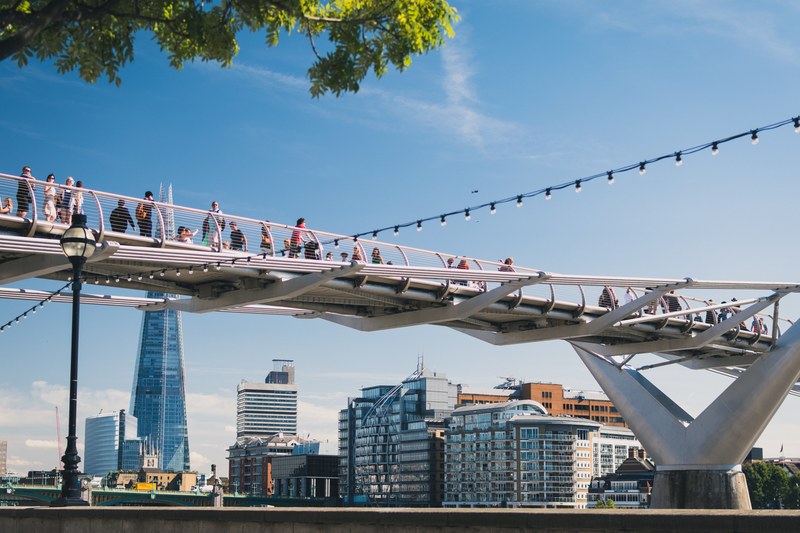 londoners walking on the millennium bridge over thames, urban suspension bridge 4k