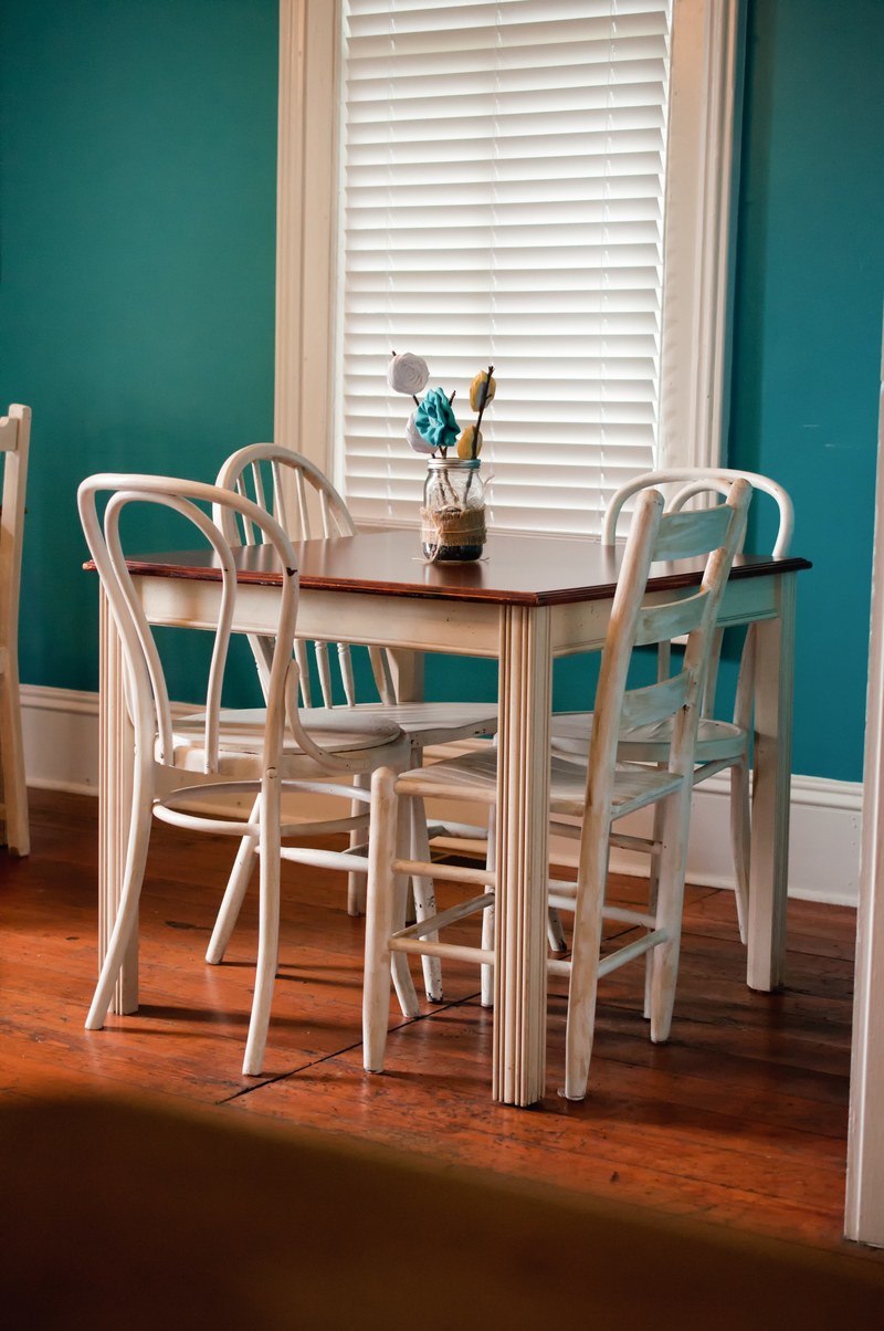 interior of a house with a small square table with a vase full of flowers and chairs with blue painted walls, vase on table with chairs 4k