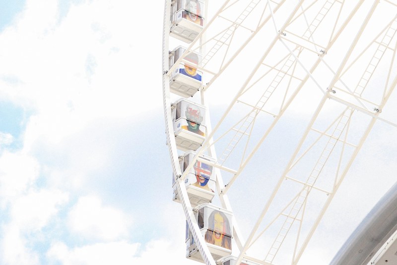a white ferris wheel with passenger cars painted with different faces on them in paris, ferris wheel with flag faces 4k