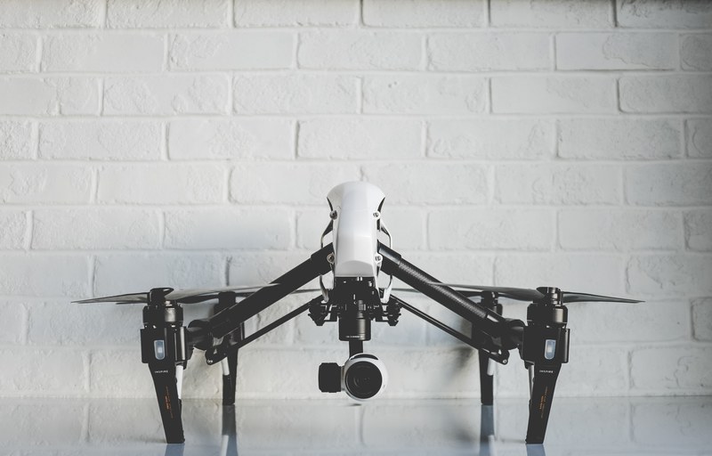 white drone resting on a shiny white surface in front of a white brick wall, drone in an office 4k