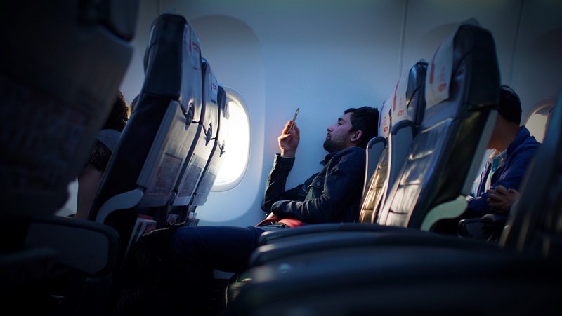 a bearded man using his phone on an airplane, checking the phone on the plane 4k