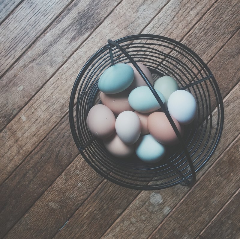 eggs of different colors are placed in a basket on a wooden panel, _basket eggs colors 4k