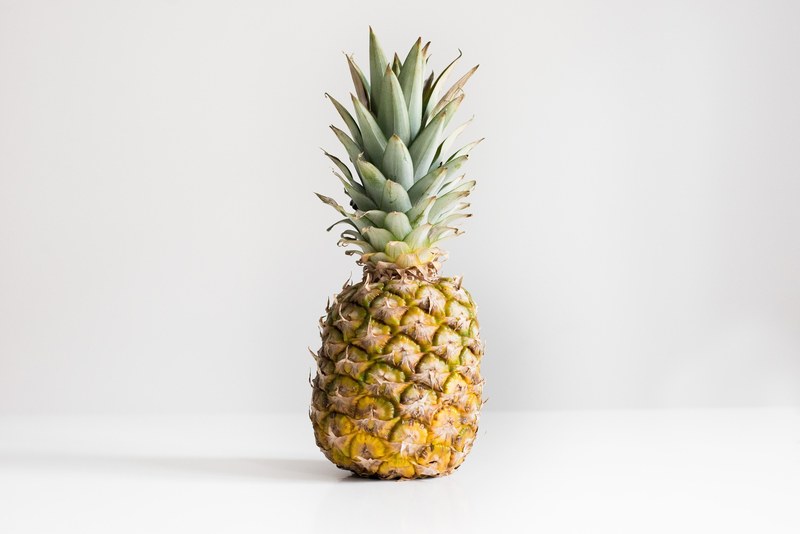 one pineapple with green top on a white background, pineapple front 4k