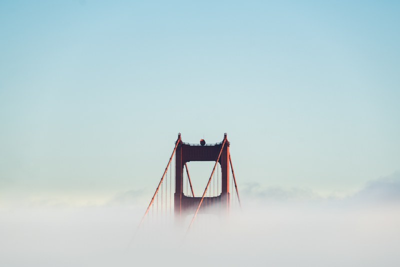 golden gate bridge breaks through the clouds on a clear blue day, emergence from the clouds 4k