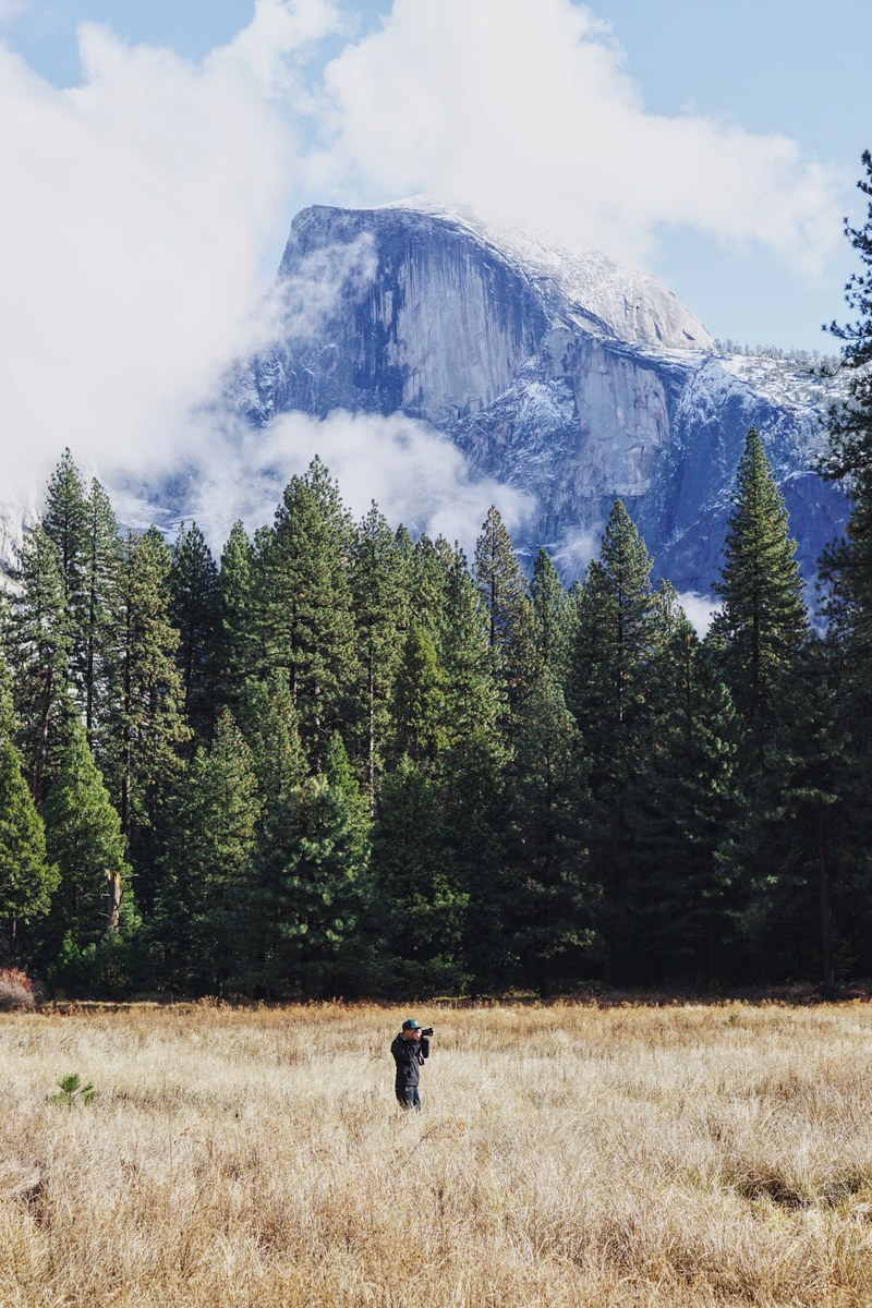a photographer standing in a field with a view on yosemites half dome, photographer near half dome 4k