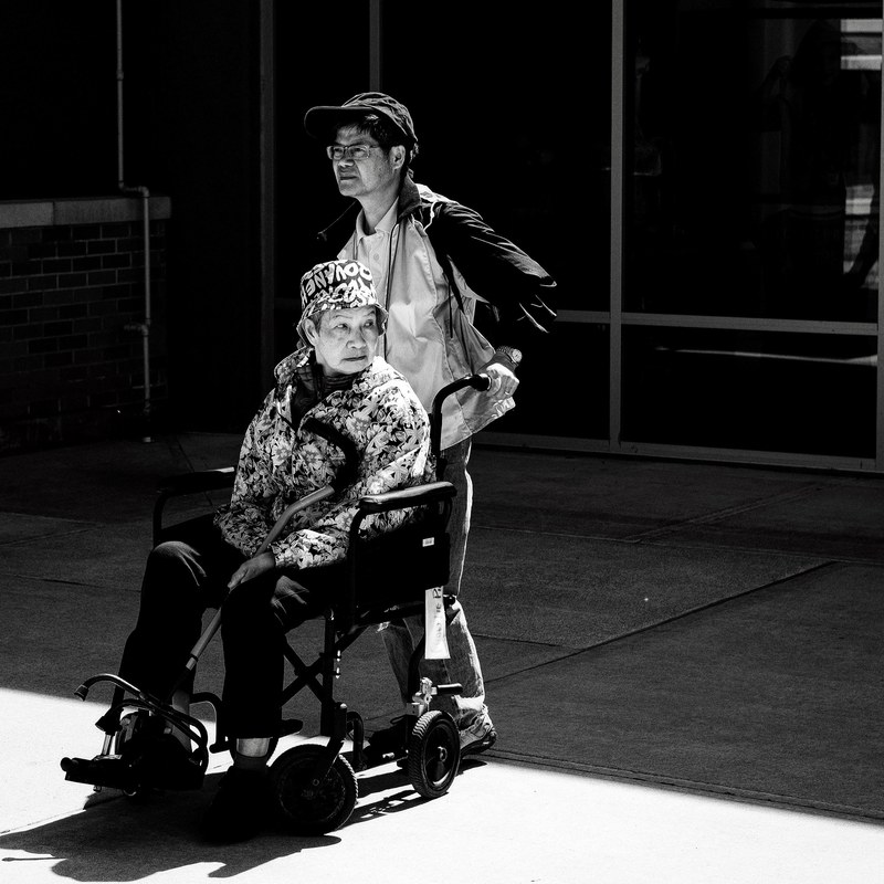 black and white photo of a man pushing a woman in a wheelchair, where is my uber 4k