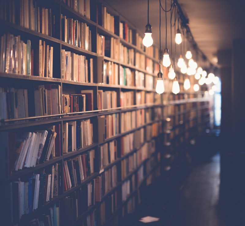 a library with filled bookshelves and blurred light bulbs hanging from the ceiling, library with hanging bulbs 4k