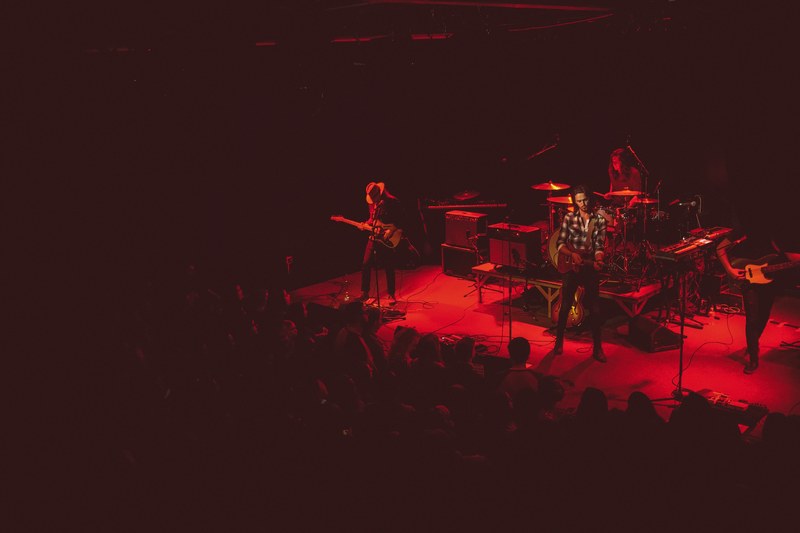 a band performing on stage under red light in metro music hall, red spotlights in metro music hall 4k