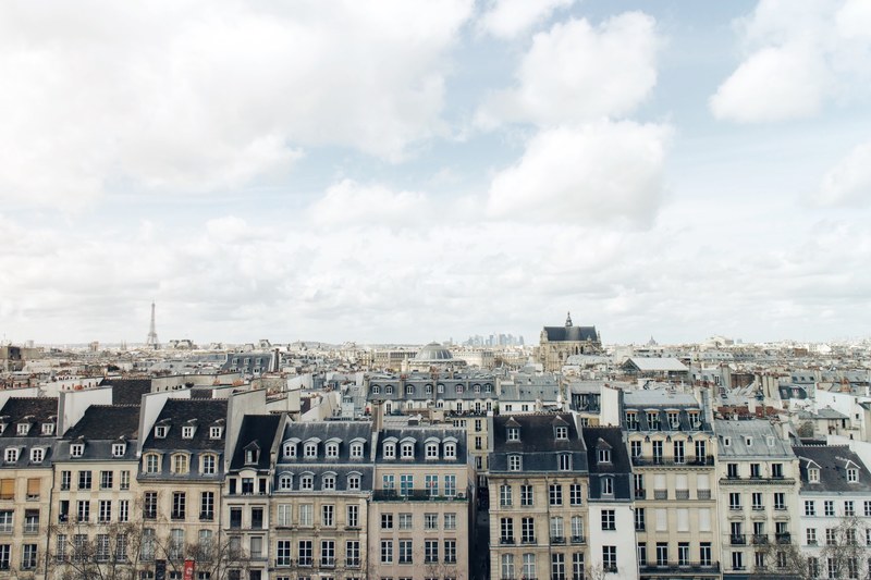 a skyline view of paris buildings on a bright day with eiffel tower in the distance, paris buildings with clouds 4k