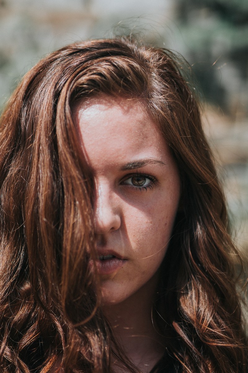 woman makes eye contact with hair covering half her face, up close and personal 4k