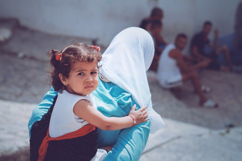 young girl being carried on her mothers back in the city, the moment of innocence 4k