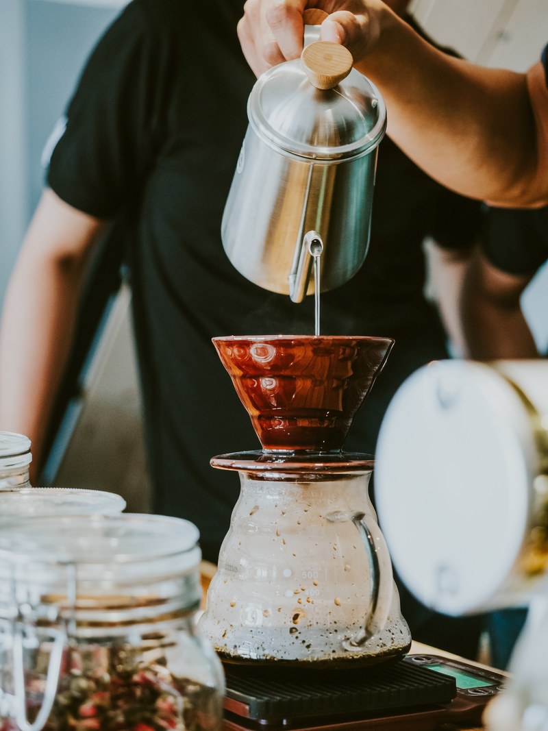 a person pouring milk over a coffee cup on top of a pot of vietnamese coffee, when in saigon 4k