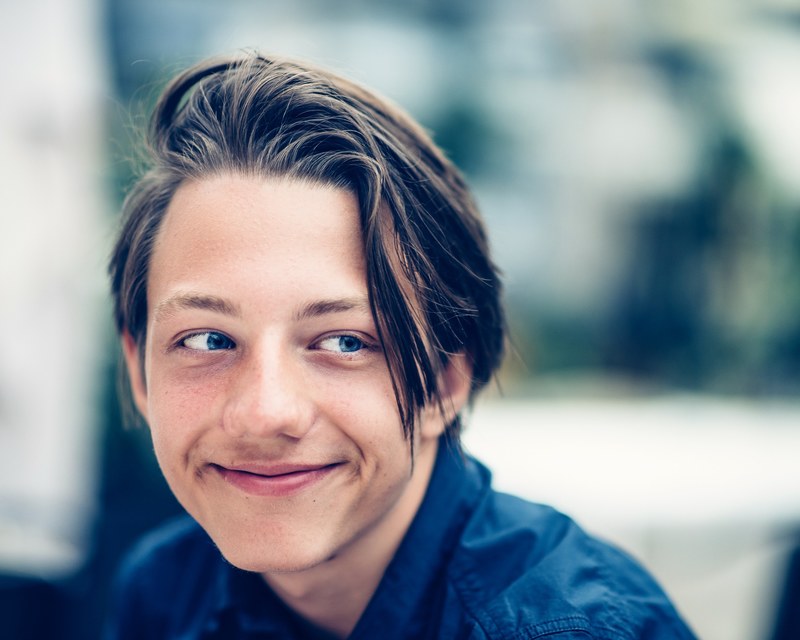 a man with long hair and blue eyes smiles while looking to the side, man looking to the side 4k