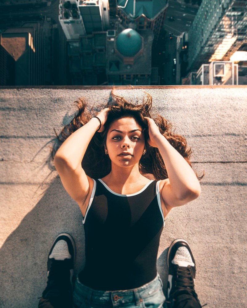 a woman laying down on the edge of a roof while a man stands above her toronto, dream 4k