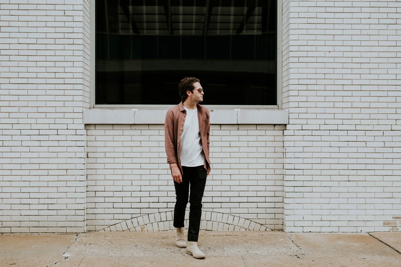 a man wearing sunglasses looks to the side in front of a white brick wall, man in front of brick wall 4k
