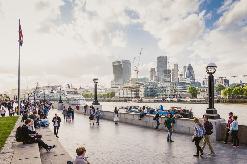 tourists strolling on the bank of thames with the city of london visible on the other shore, city hall 4k