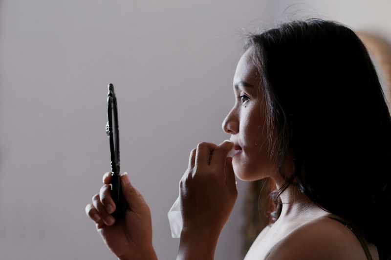 a woman dabs her mouth with a napkin while holding a hand mirror in bekasi, _make up for wedding 4k