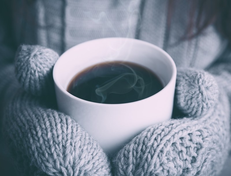 a person in mittens holding a cup of hot coffee, hot coffee on a cold day 4k