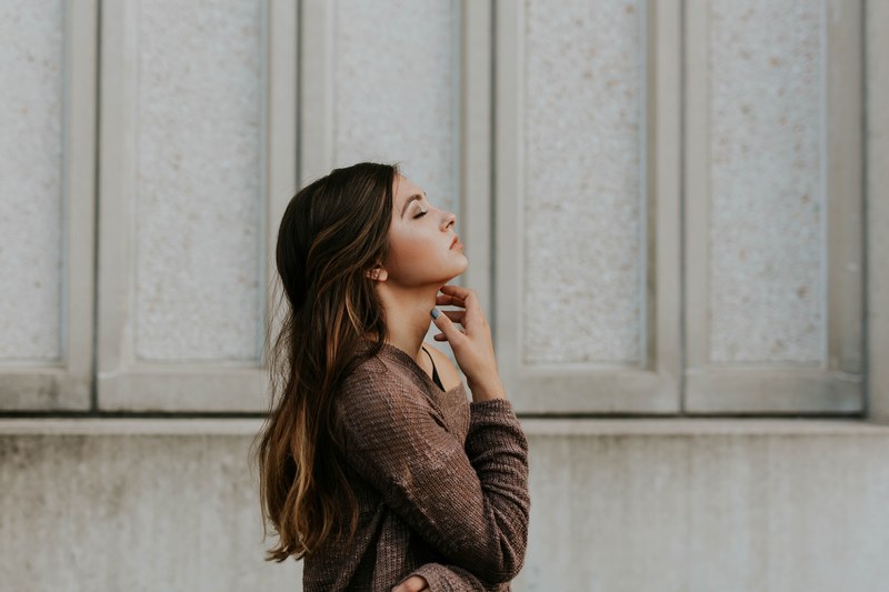 woman closing her eyes and relaxing on a walk outside, practicing self care 4k