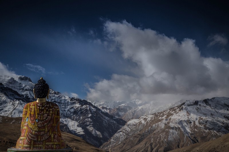 sitting buddha overlooking open mountains and land with clouds above, buddha in mountains 4k