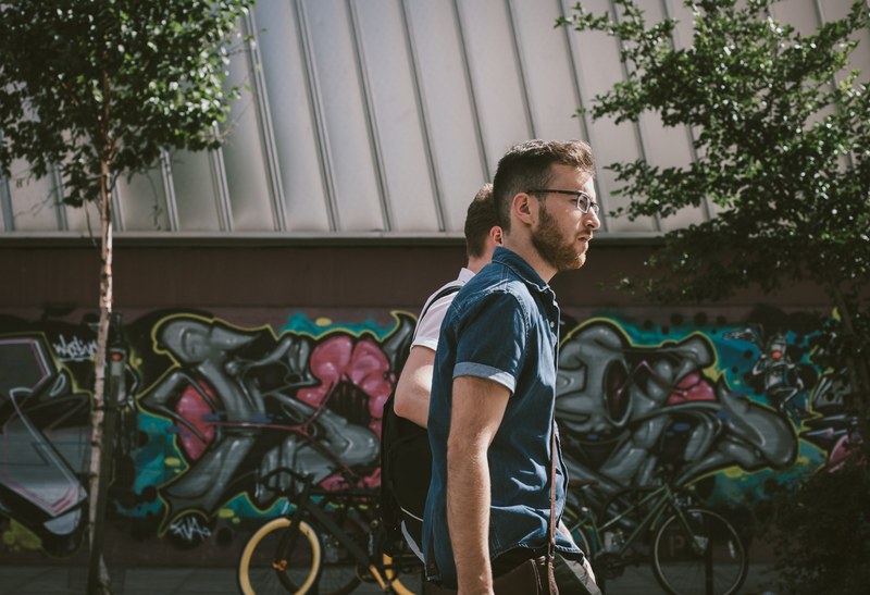 two guys walking by a graffiti wall in shoreditch where a number of bikes are parked, walk on by 4k