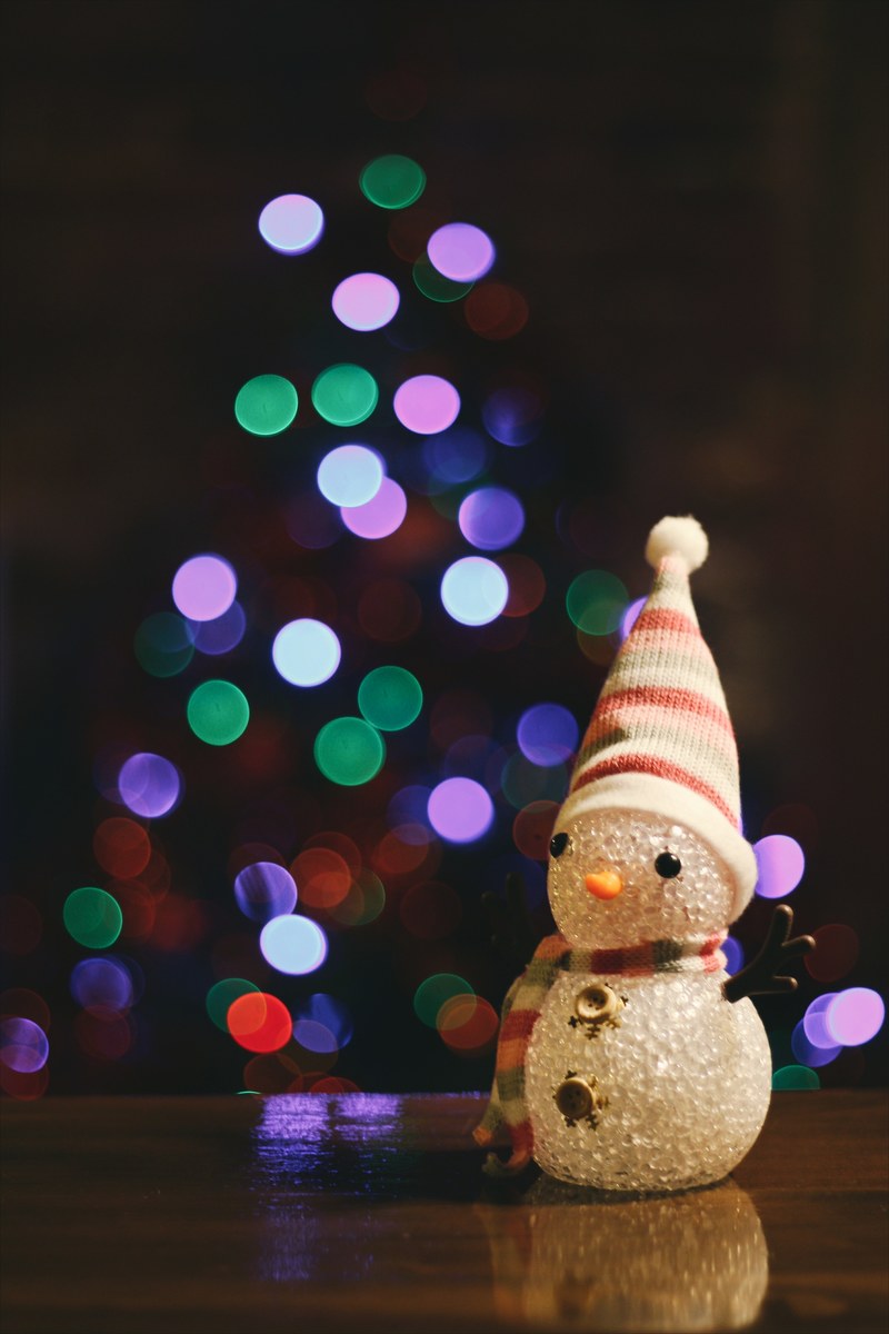a little snowman figure sitting on the floor in front of a christmas tree, _snowman in front of xmas tree 4k