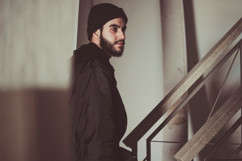 man with a beard wearing a hat walking up an industrial staircase, beard and beanie 4k