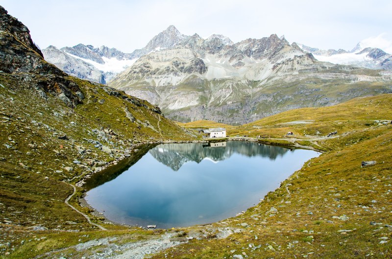 a cabin on the side of a small lake in the mountains in zermatt, quiet lakeside cabin 4k