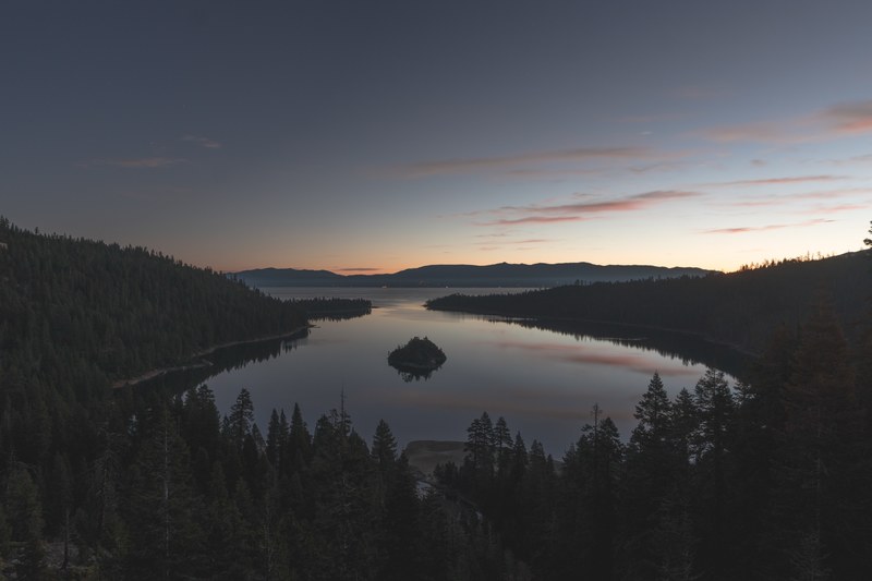 a calm lake situated in the forest of emerald bay lake tahoe reflecting the sunset on its waters, calm lake at emerald bay 4k