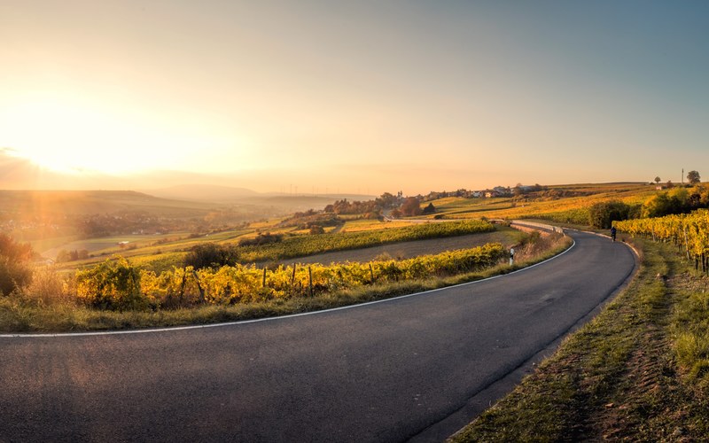 a sunset shines upon a winding asphalt road in mlsheim germany and the many fields surrounding it, sunset in mlsheim germany 4k