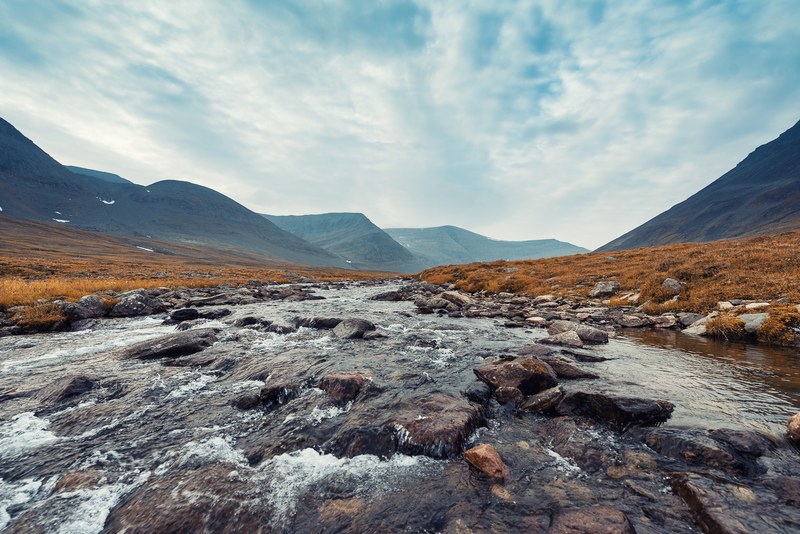a stream flowing on a rocky bed in the middle of a mountain valley in treriksrset, treriksrset 4k