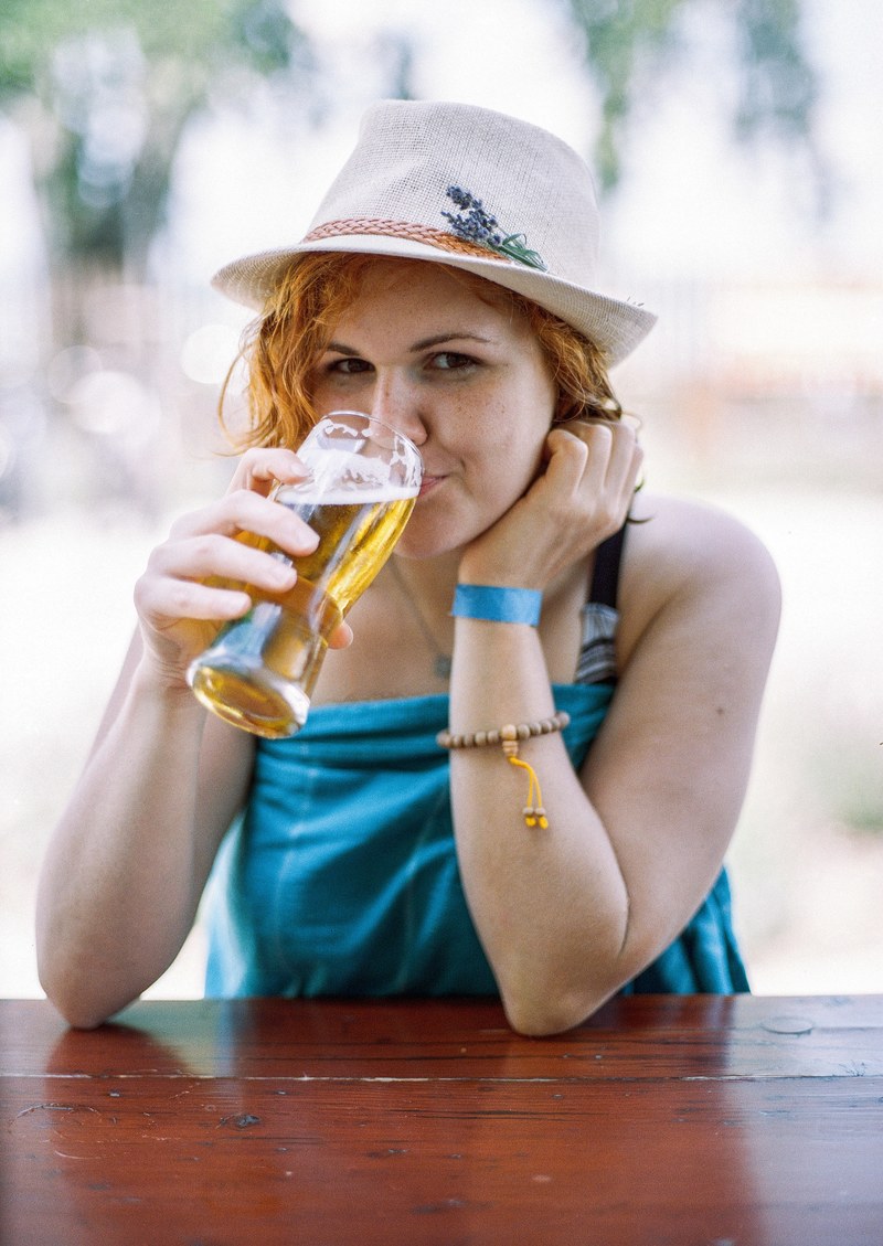 woman in a hat sips on a pint of beer on a restaurant patio, summer chill 4k