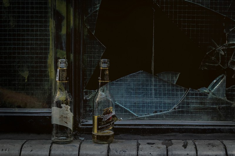 two beer bottles in front of a broken glass window, beer bottles by window 4k