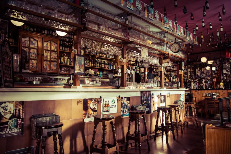 the interior of a bar with stools glass cups and empty bottles attached to the roof in madrid, cerveceria la mayor 4k