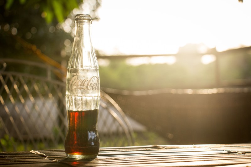 a glass bottle of coca cola on a table during golden hour, coca cola bottle 4k