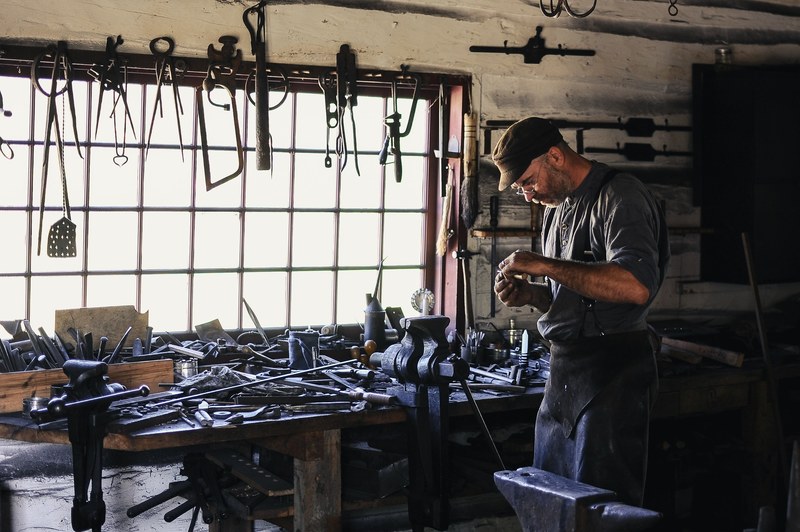 a middle aged man working near a workbench with various tools on it in a workshop, busy craftsman 4k
