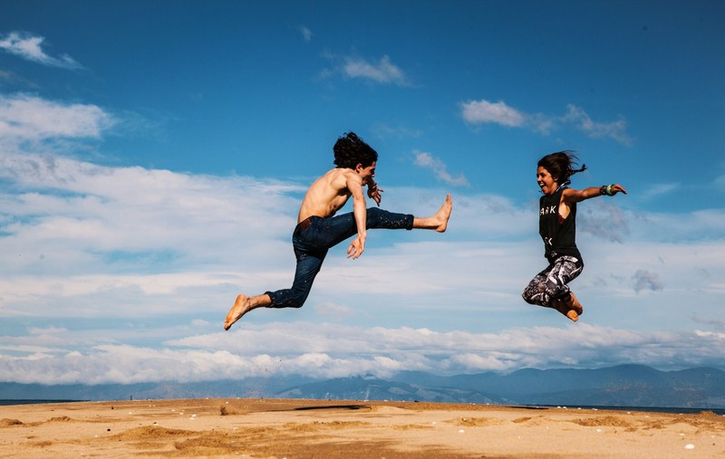 a couple jumping really high in the sky kicking their feet up at abel tasman national park, abel tasman national park 4k