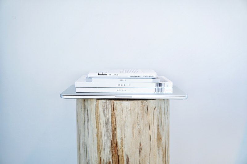 four books with white covers on top of a macbook on a log, minimal reading list 4k