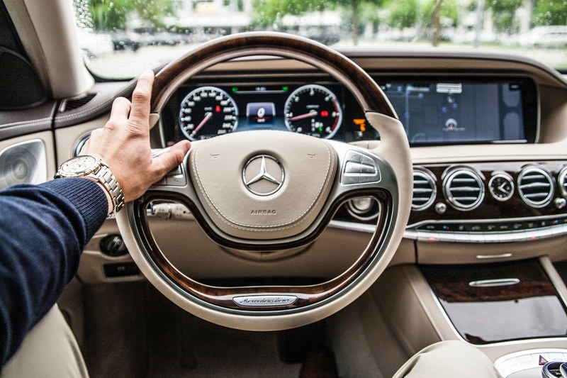 a driver with his hand on the steering wheel of a mercedes benz car, driving a mercedes 4k