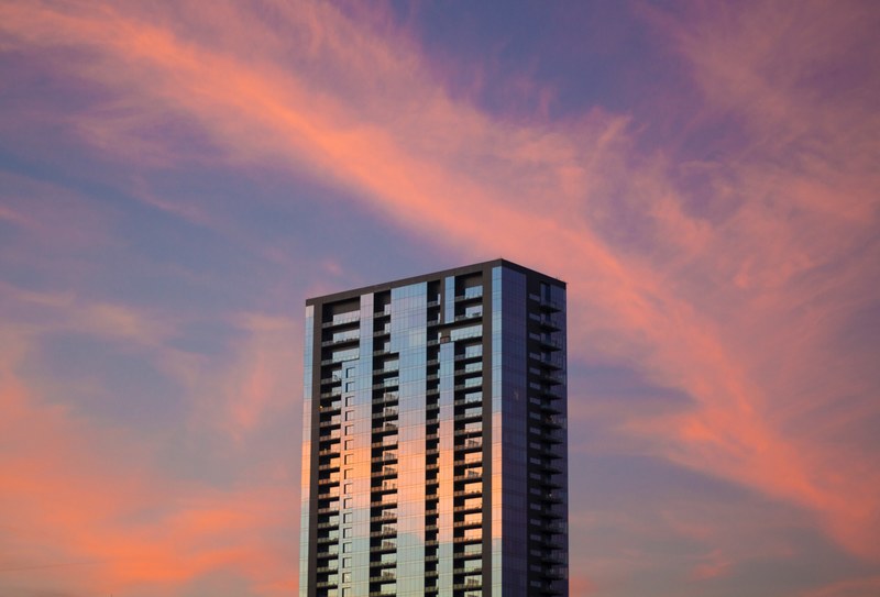 a skyscraper reflecting the purple and pink cloudy sky at sunset in austin, skyscraper reflections 4k