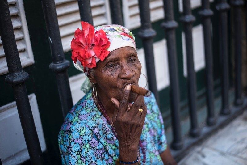 a woman wearing a headscarf with a flower smoking a cigar, cuban cigar 4k