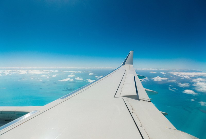 a view from an airplane window on its wing with open wings flaps over patchy clouds, view on the wing flaps 4k