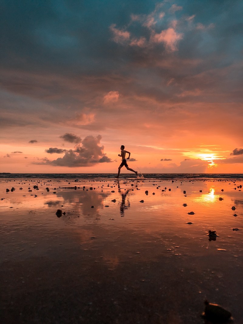 man running on the wet sand coast at aksa beach at sunset, changing tone_ 4k