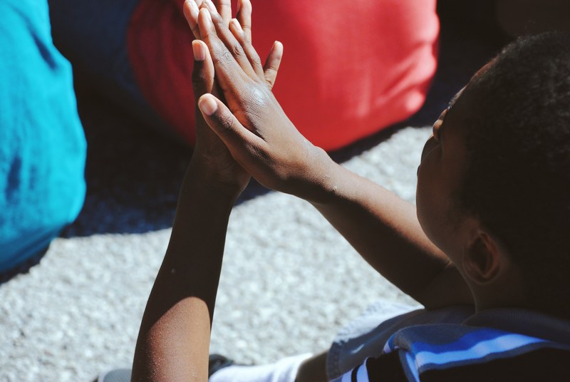 a boy sitting on the ground behind other students claps his hands, _a boy clapping 4k