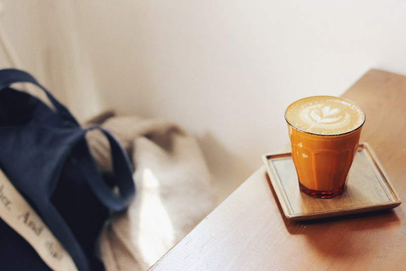 a cup of coffee with a latte artwork on a wooden coaster on a table, moon coffee 4k