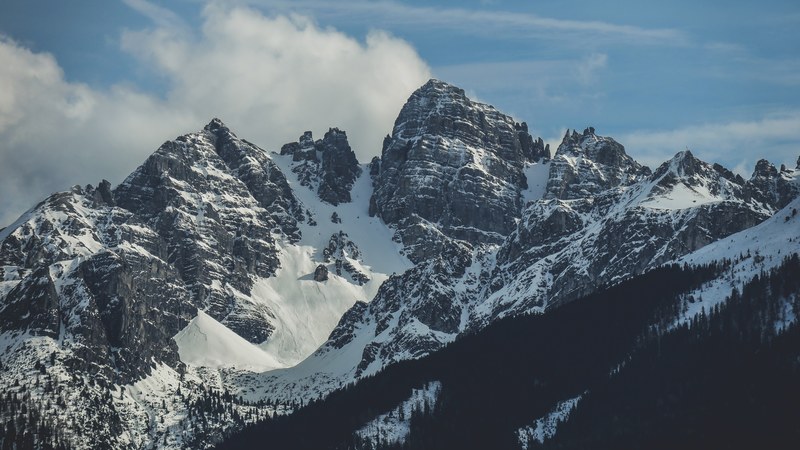 a snowy mountain with craggy rock towers under a blue sky, springs finally here sort of_ 4k