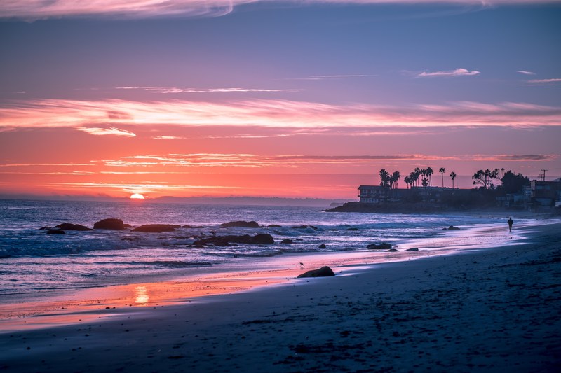 a pink sky and the sun going down on the horizon and the sea at malibu beach, palm trees and water_ 4k