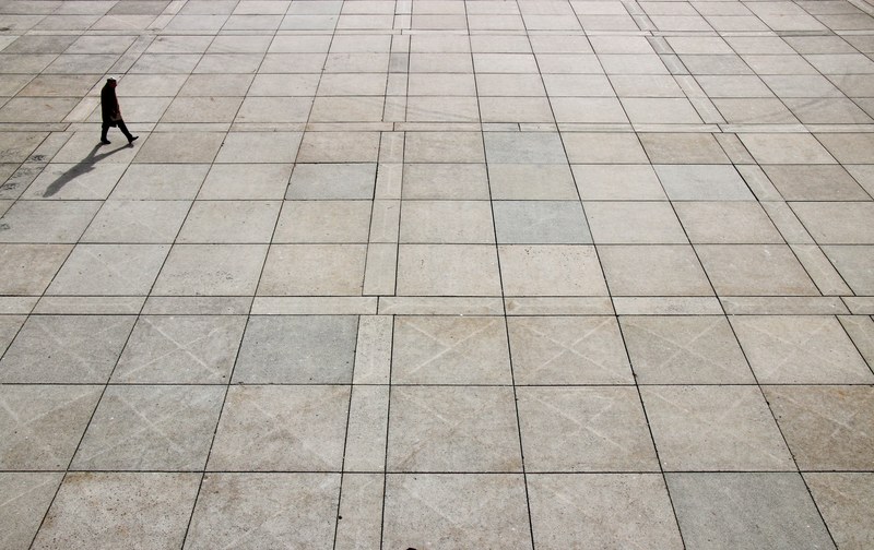a high shot of a lone person walking across a large plaza, no one is alone 4k