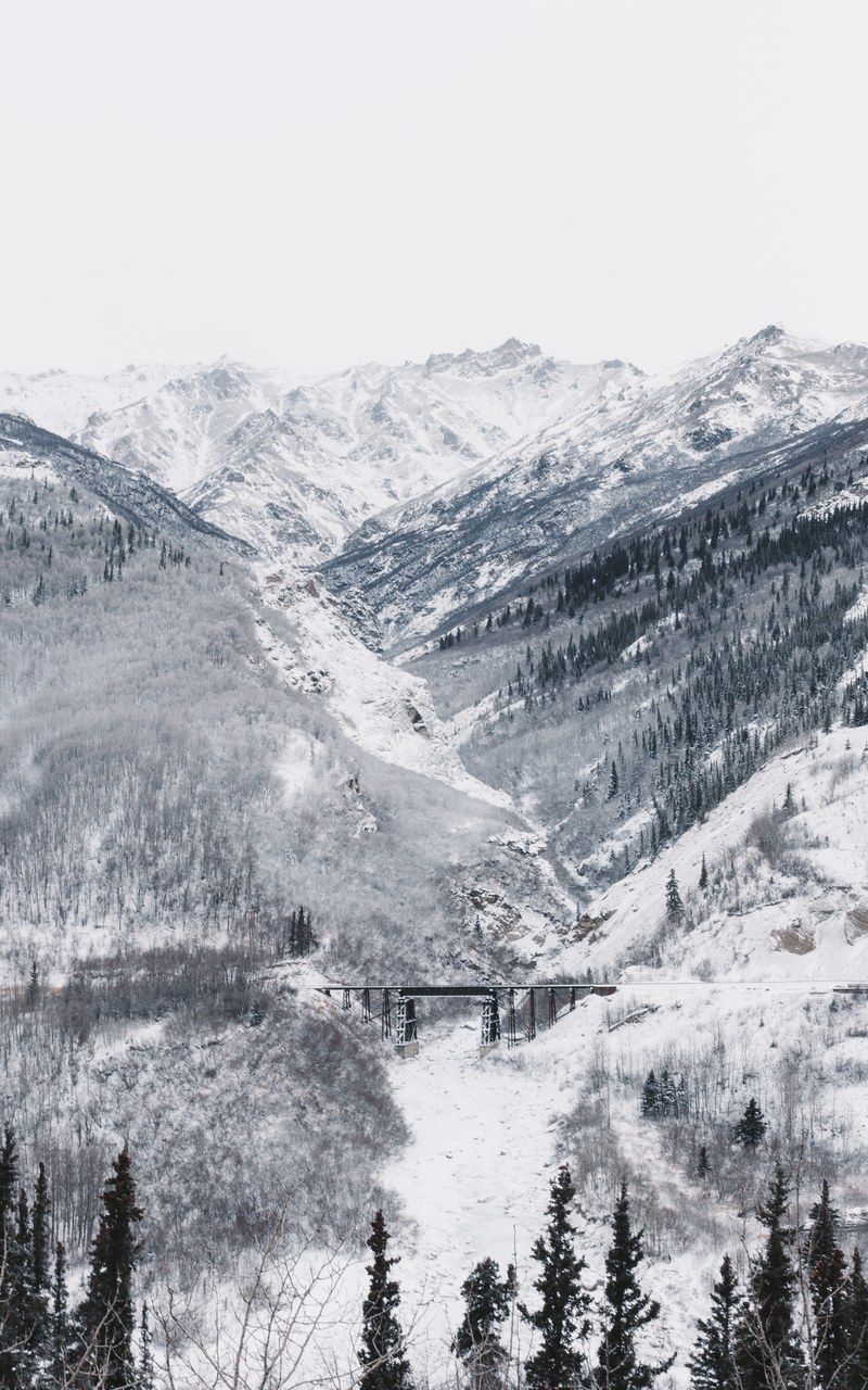 a distant shot of a bridge in a snowy mountain valley, bridge in a silver valley 4k